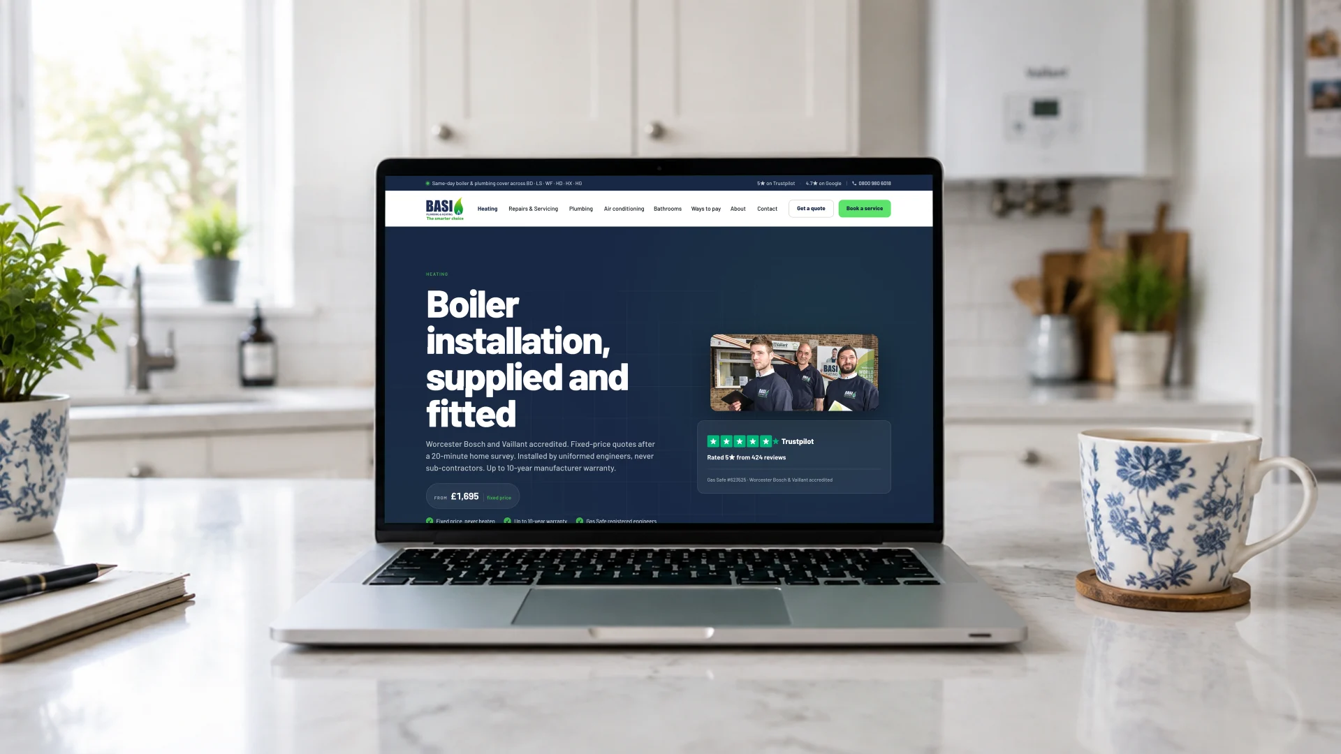 A laptop on a kitchen worktop showing the BASI Heating boiler installation page with its fixed price and Trustpilot rating