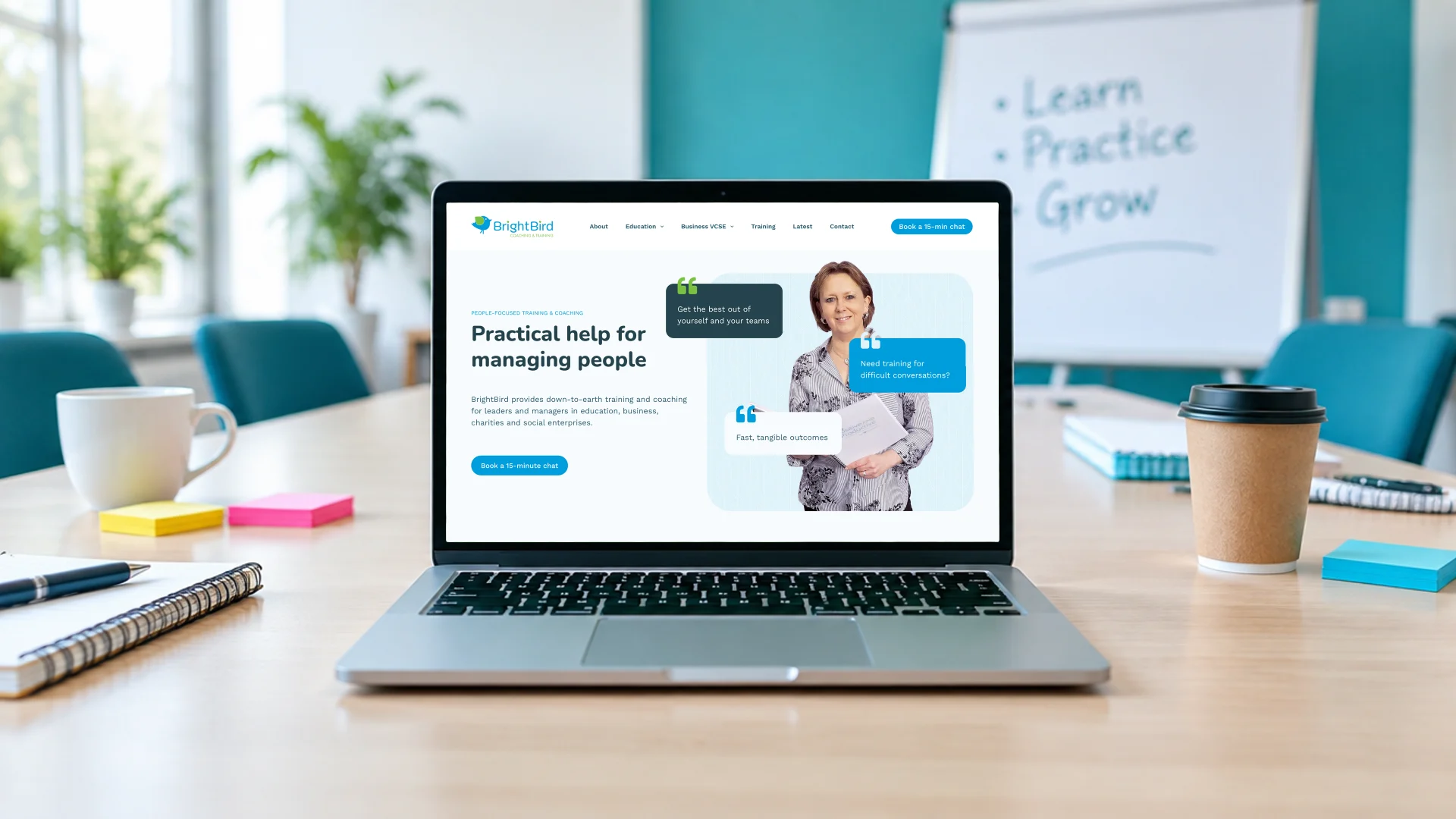 A laptop on a training room table showing the BrightBird homepage: Practical help for managing people, with a Book a 15-minute chat button