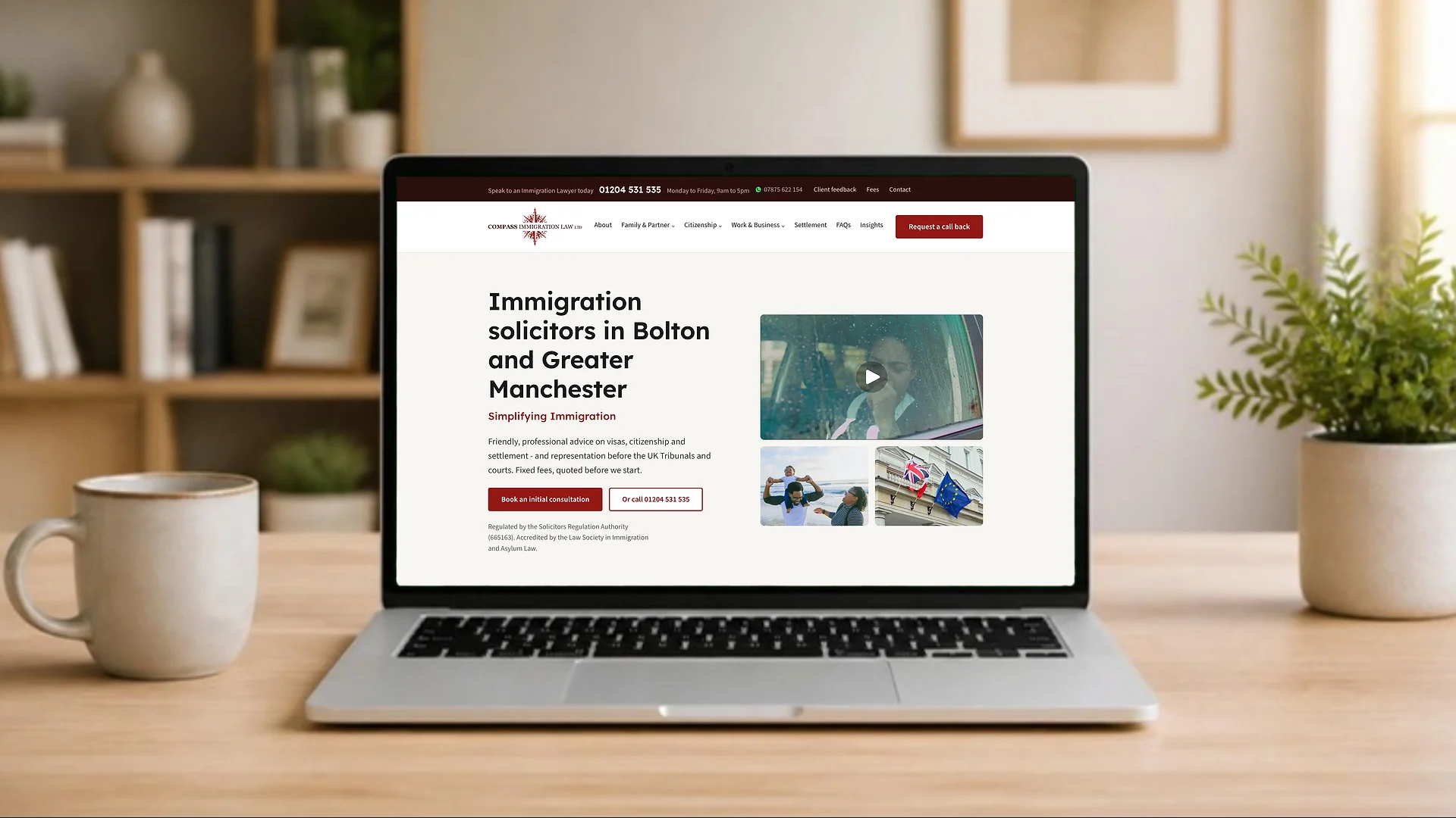 A laptop on a desk showing the Compass Immigration Law homepage: plain headline, phone number in the top bar and a clear book a consultation button