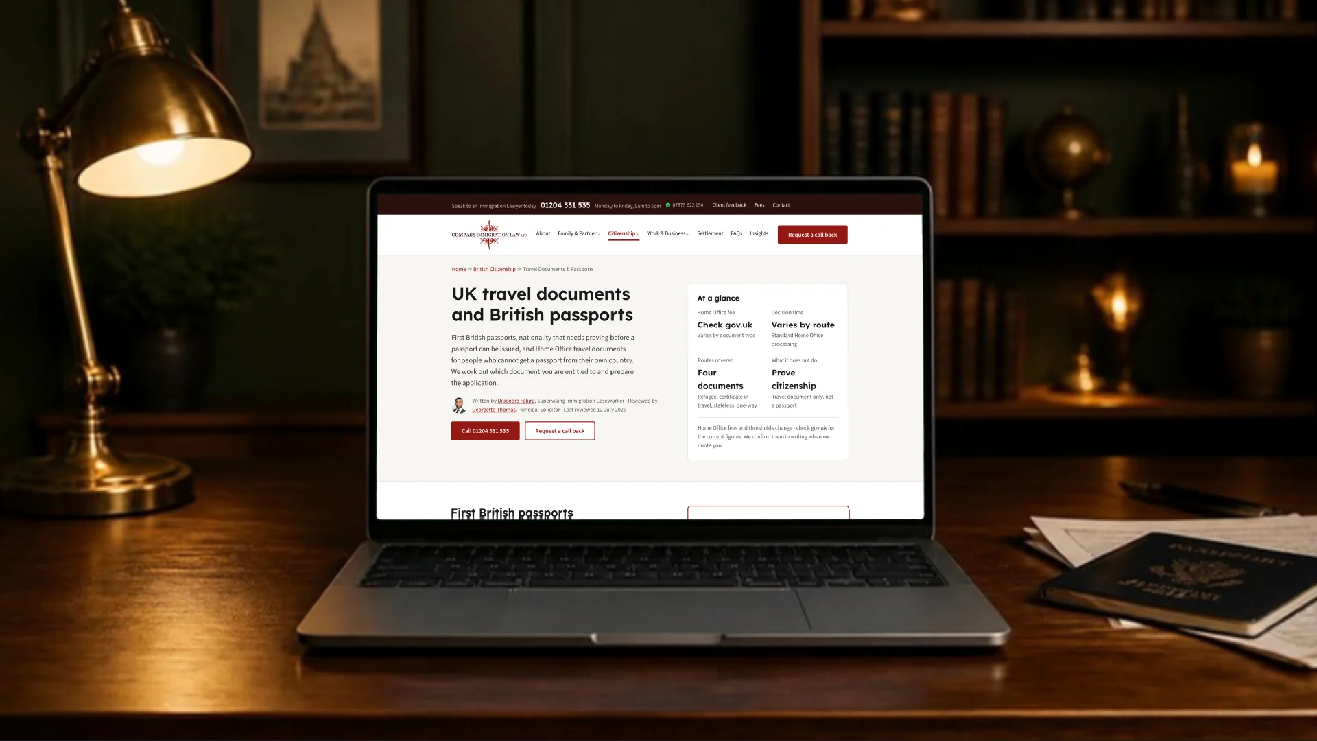 A laptop on a lamp-lit desk beside a passport, showing the Compass travel documents page with its at-a-glance panel, named author and reviewing solicitor