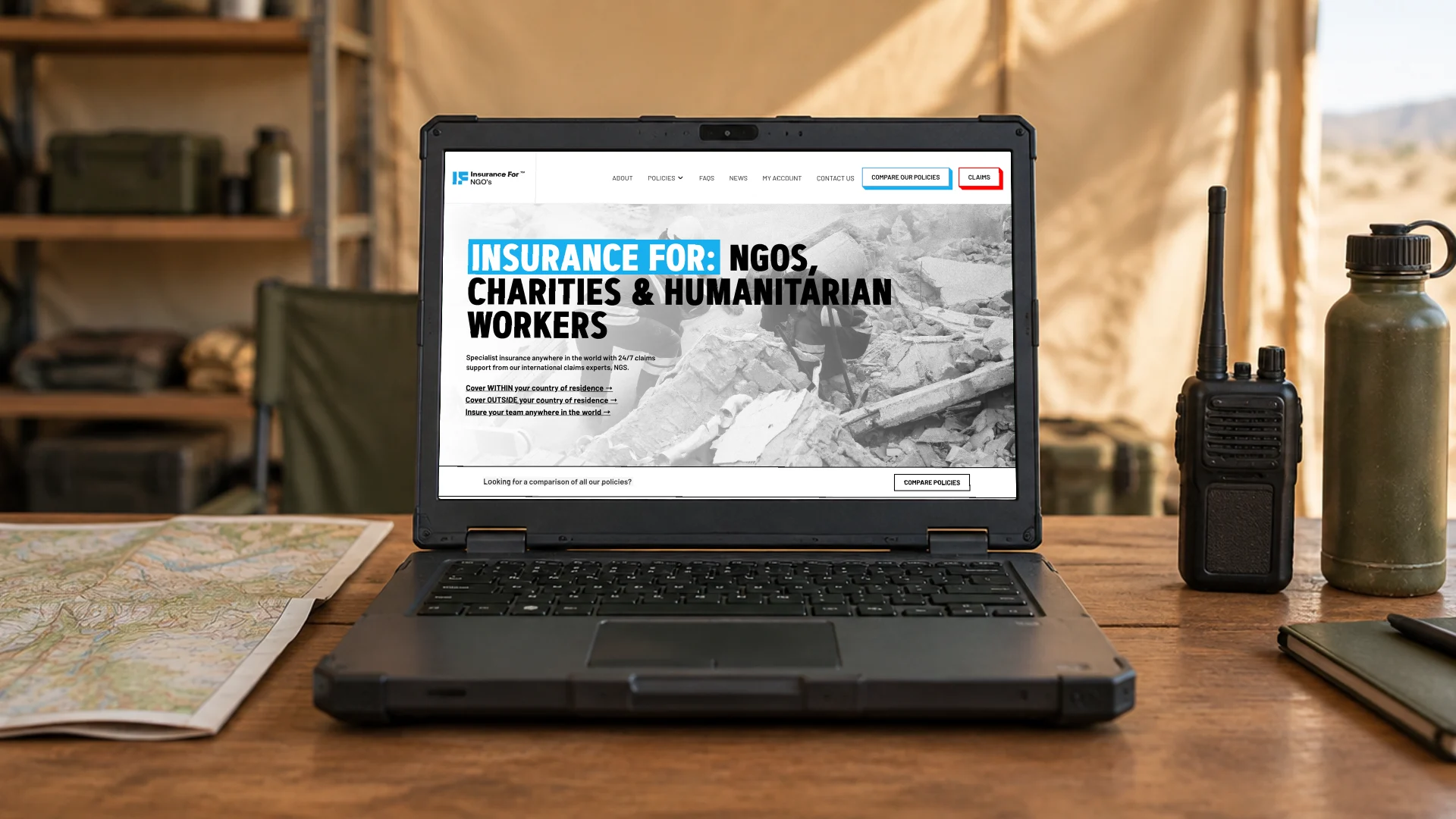 A rugged laptop on a field office desk beside a map and radio, showing the Insurance for NGOs homepage