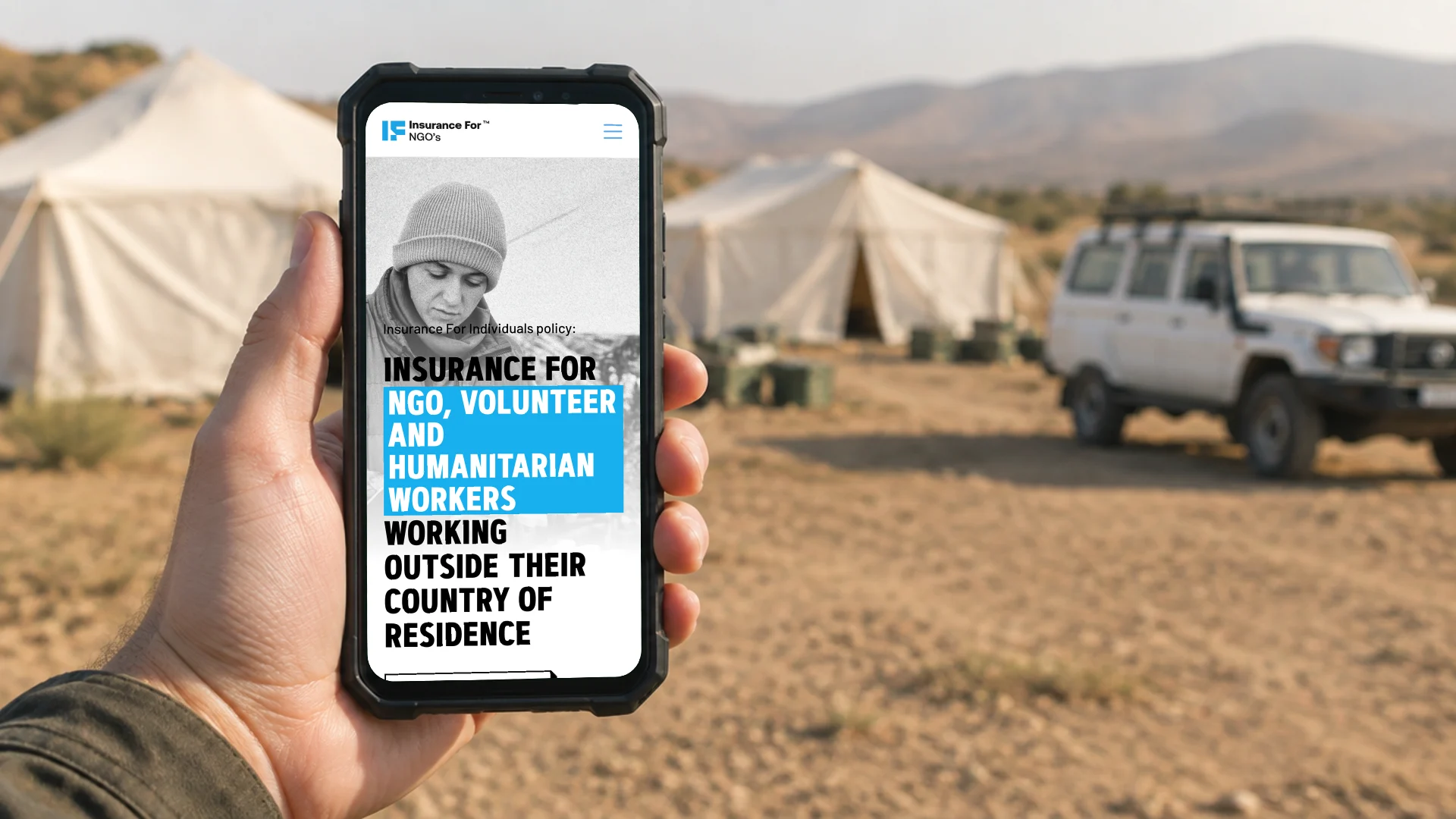 A hand holding a phone at a remote field base, showing the Insurance for NGOs page for workers outside their country of residence